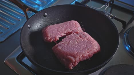 chef puts raw ground turkey meat into pan greased with oil for cooking