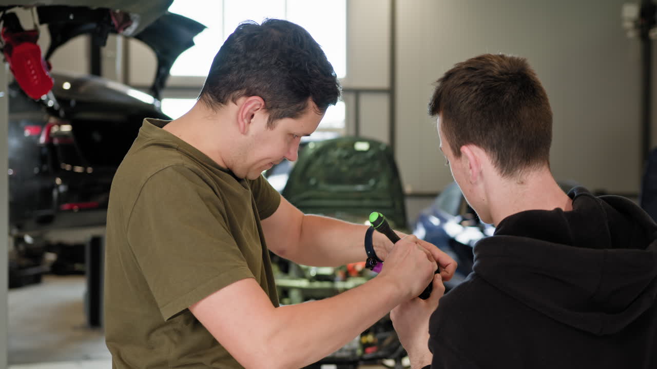 dos mecánicos trabajando en un coche en un taller de reparación