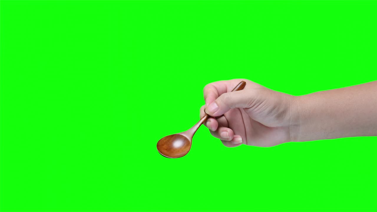 Hand holding wooden spoon on green screen background
