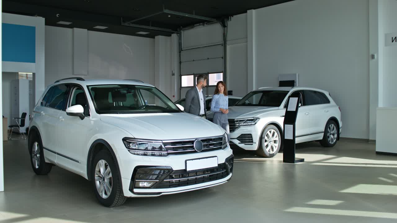 vendedor de automóviles mostrando el suv al cliente en la sala de exposiciones