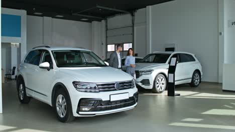 car salesperson showing suv to customer in showroom