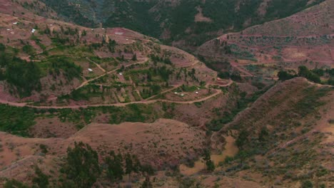 The-Kirkas-community-near-Cuzco,-Peru,-aerial-over-golden-mountains,-boom-jib-down