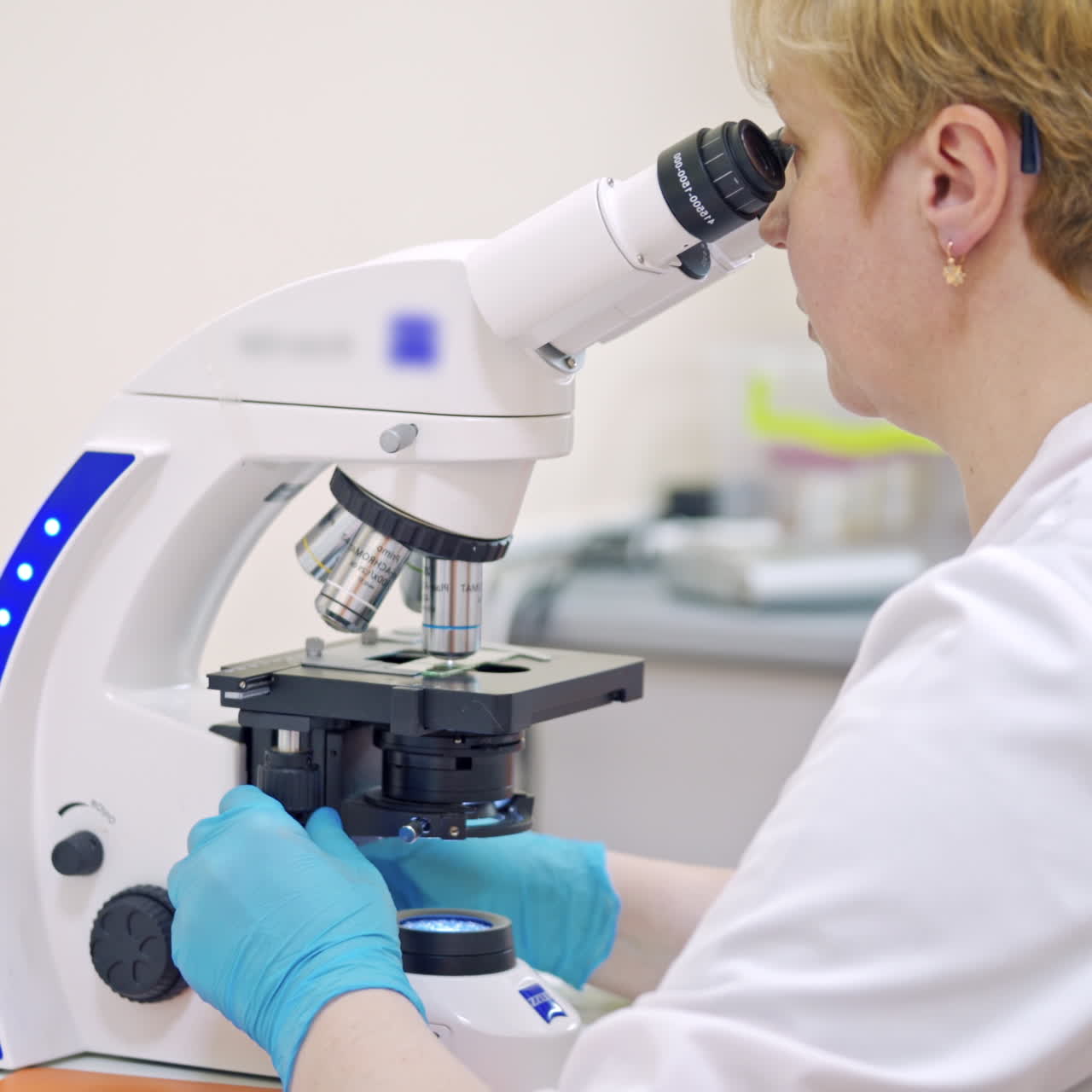 Laboratory assistant with microscope in medical center. Female scientist is making researches with samples through the microscope.