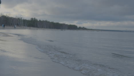 Slow-motion-shot-of-walking-person-with-gumboot-inside-water-of-ocean-during-cloudy-day-in-Poland