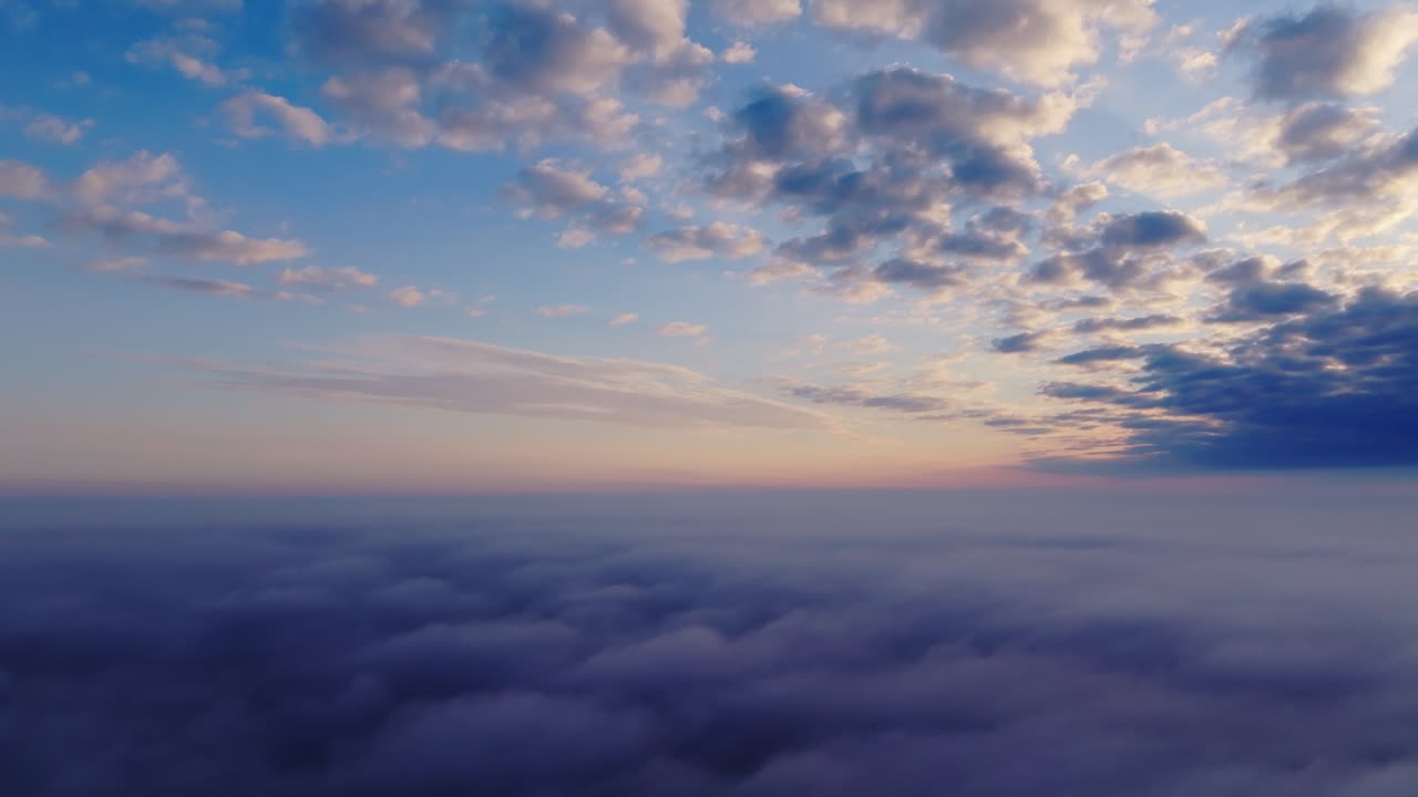 Ethereal cloud layer at sunrise as drone ascends revealing pastel sky and calm