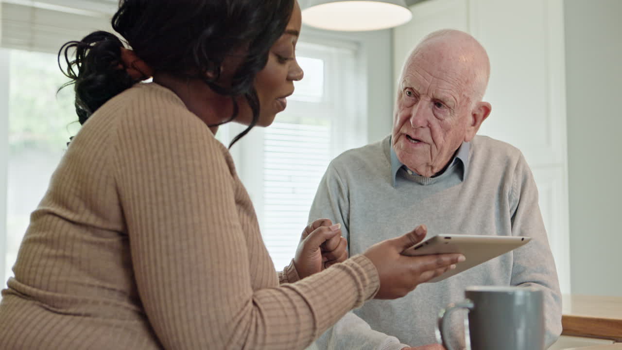 Elderly man learning to use a tablet with caregiver