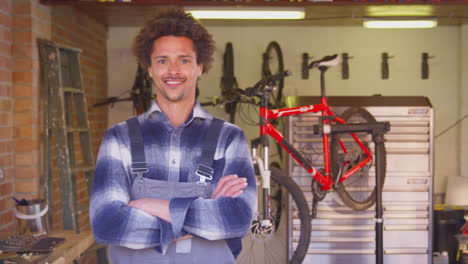 portrait of man in garage at home with cycle hanging on wall behind