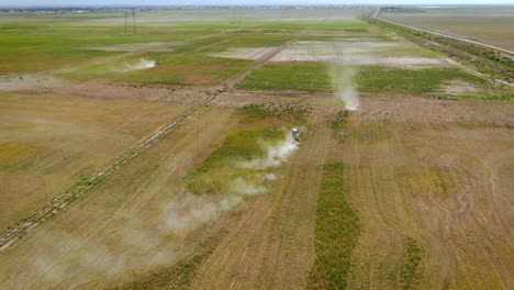 panoramic view of agriculture field with tractors mowing weeds - aerial drone shot