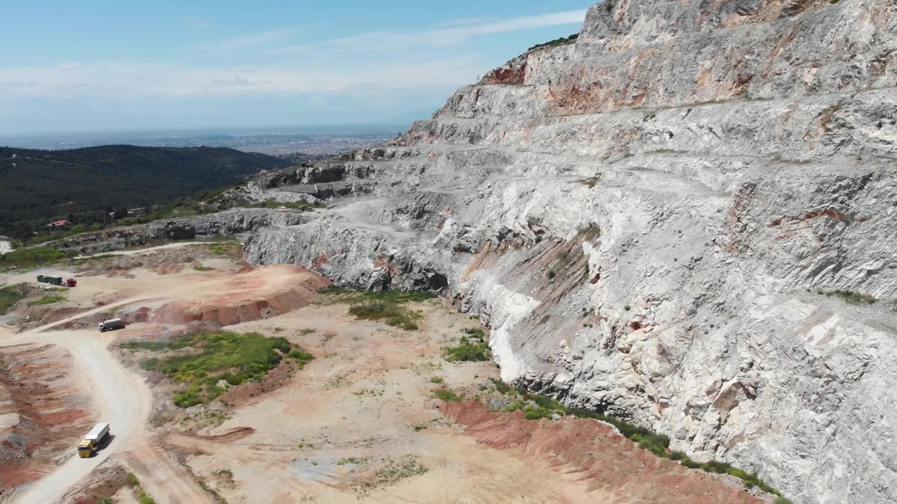 Ripidi strati rocciosi formano un motivo suggestivo sotto cieli azzurri in una vasta cava. Ideale per studi geologici o documentari industriali