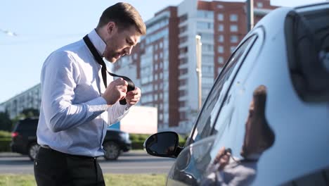 a bearded business man in a white shirt is tying a tie near his car a bearded business man in a white shirt is tying a tie near his car he is in a hurry for a business meeting business manager