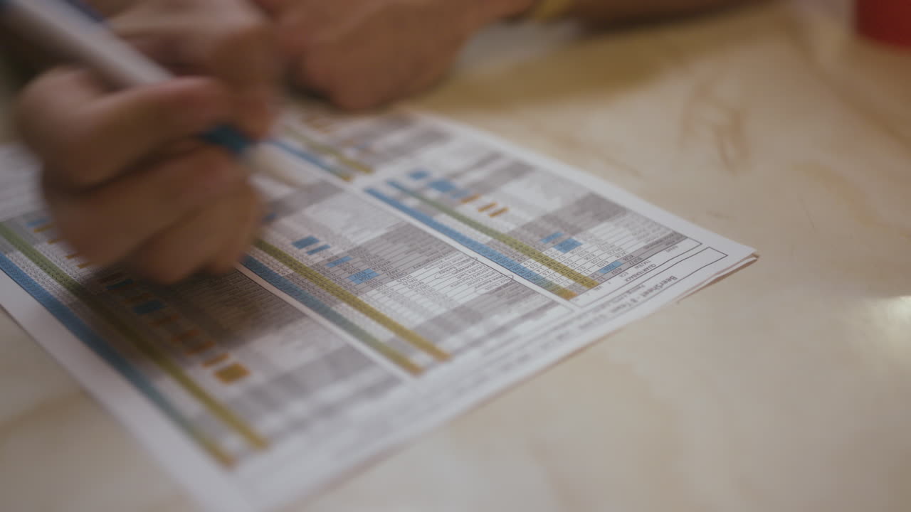 un hombre tacha y circula los nombres en una hoja de clasificación de fútbol de fantasía