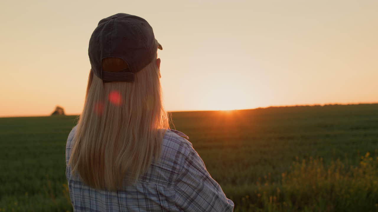 vista trasera de una mujer admirando el amanecer sobre un campo de trigo