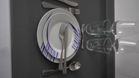 aesthetic shot of clean cutlery, white dishes and shiny glass and wine cups at table seating