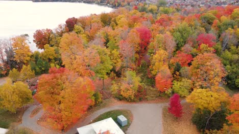 Blick-Aus-Der-Vogelperspektive-Auf-Einen-Park-Voller-Leuchtender-Herbstblätter,-Die-Im-Ganzen-Park-Verstreut-Sind,-Und-Auf-Die-Kinder,-Die-Auf-Den-Bunten-Klettergerüsten-Rennen-Und-Springen