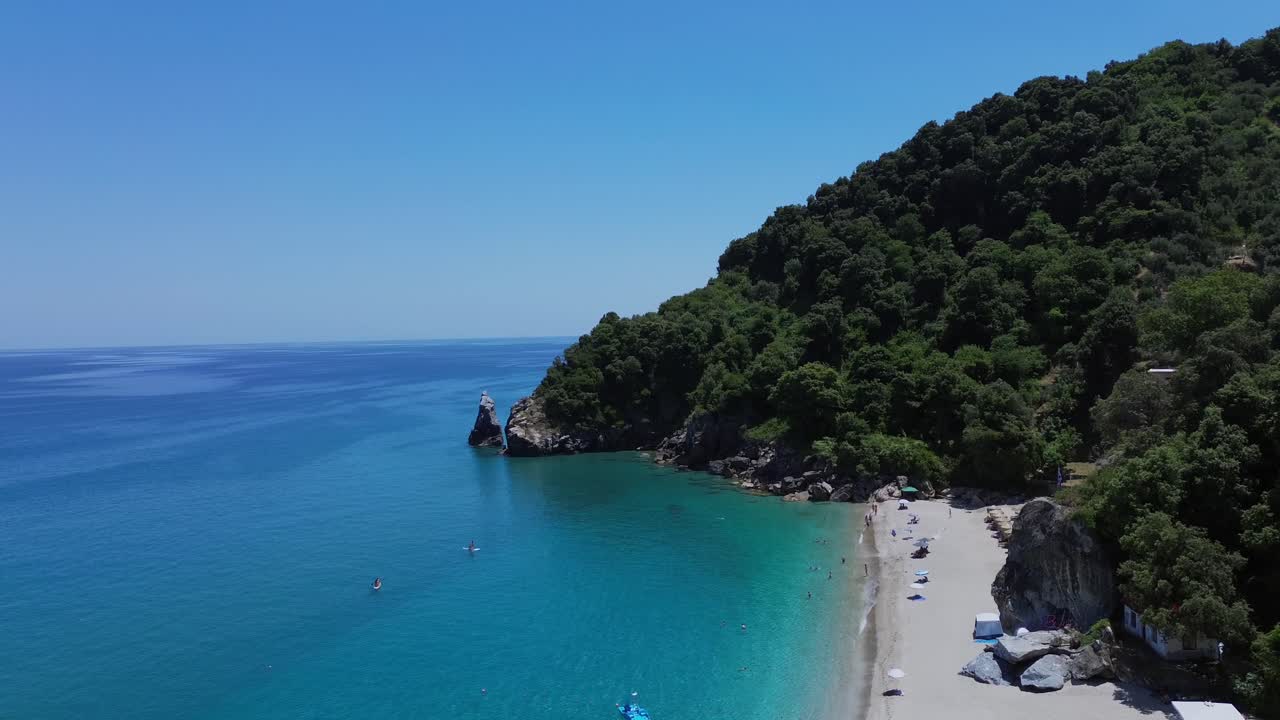 Ripresa cinematografica con drone della spiaggia di Agii Saranta a Pelio. Vista dall'alto della sabbia bianca, dell'acqua turchese e delle rigogliose scogliere verdi che incontrano il Mar Egeo. Ideale per narrazioni di viaggio e turismo.