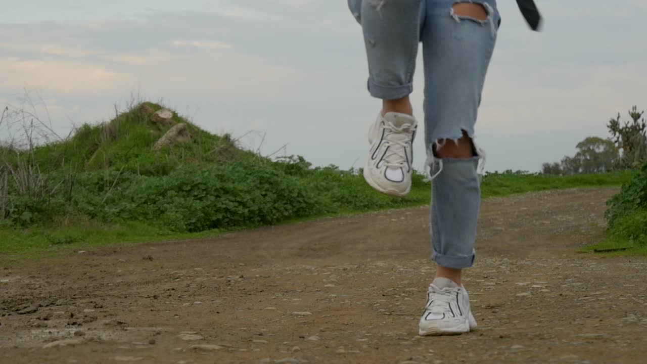 Woman Jumping in Ripped Jeans and White Sneakers