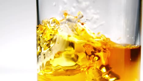 ice falling into tumbler of whiskey and ice