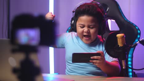 asian little boy playing video game with mobile phone then celebrating while live stream