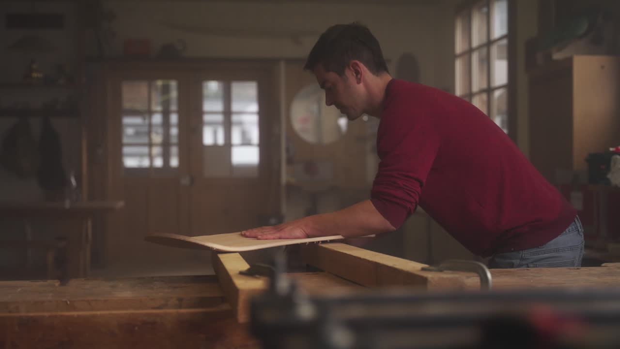 A Carpenter Sanding Plywood in His Workshop