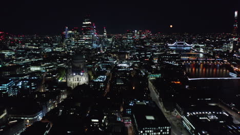 Backwards-tilt-up-reveal-of-night-cityscape.-City-lights-of-large-town.-Saint-Pauls-Cathedral,-modern-skyscrapers-and-bridges-over-Thames-river.-London,-UK