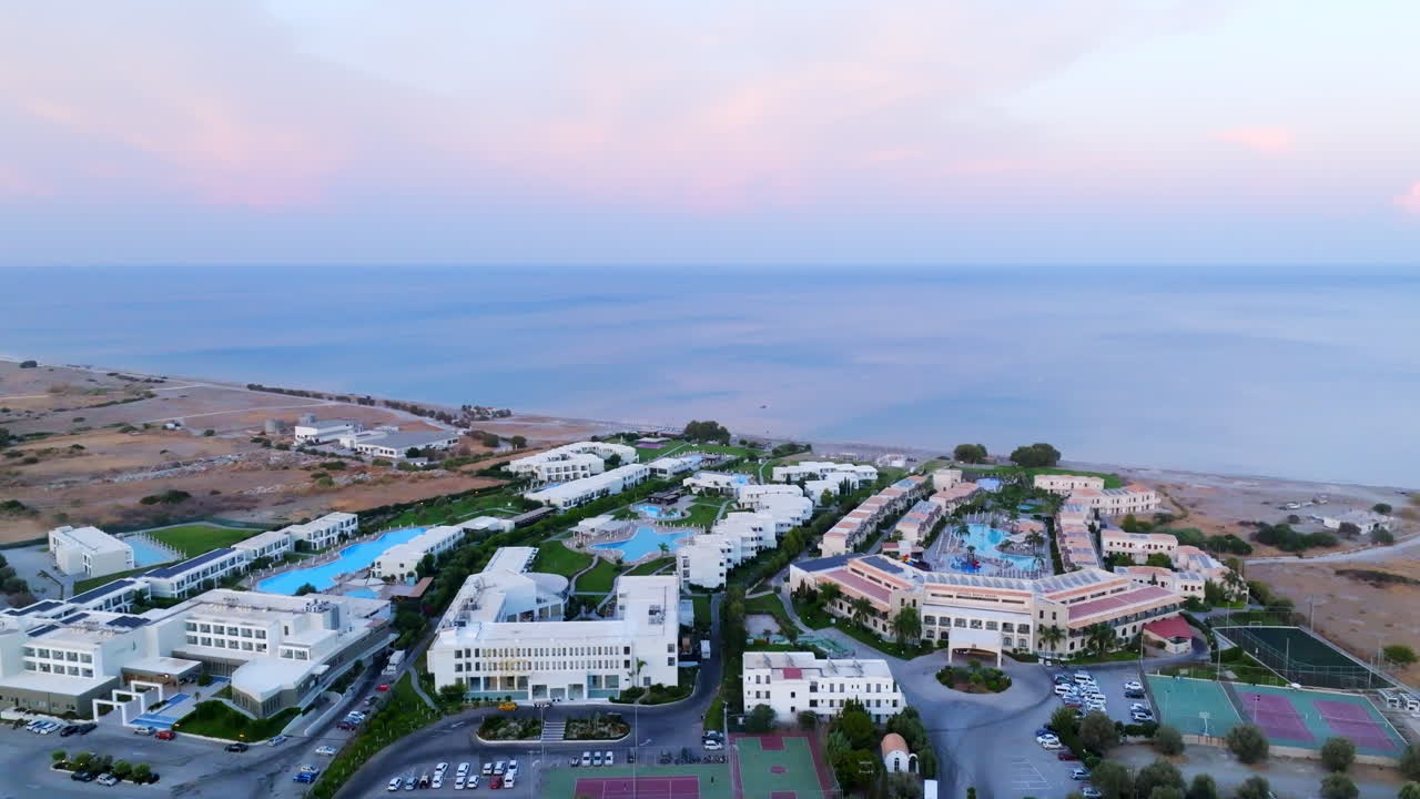Drone rising around hotel complexes, dusk on the coastline of Rhodes, Greece