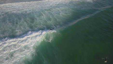 Aerial-overhead-view-with-surfers-and-wave-in-ocean-in-the-Portugal-coast,-Cascais,-Guincho