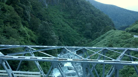 aerial view of metal bridge over narrow rocky valley with the river