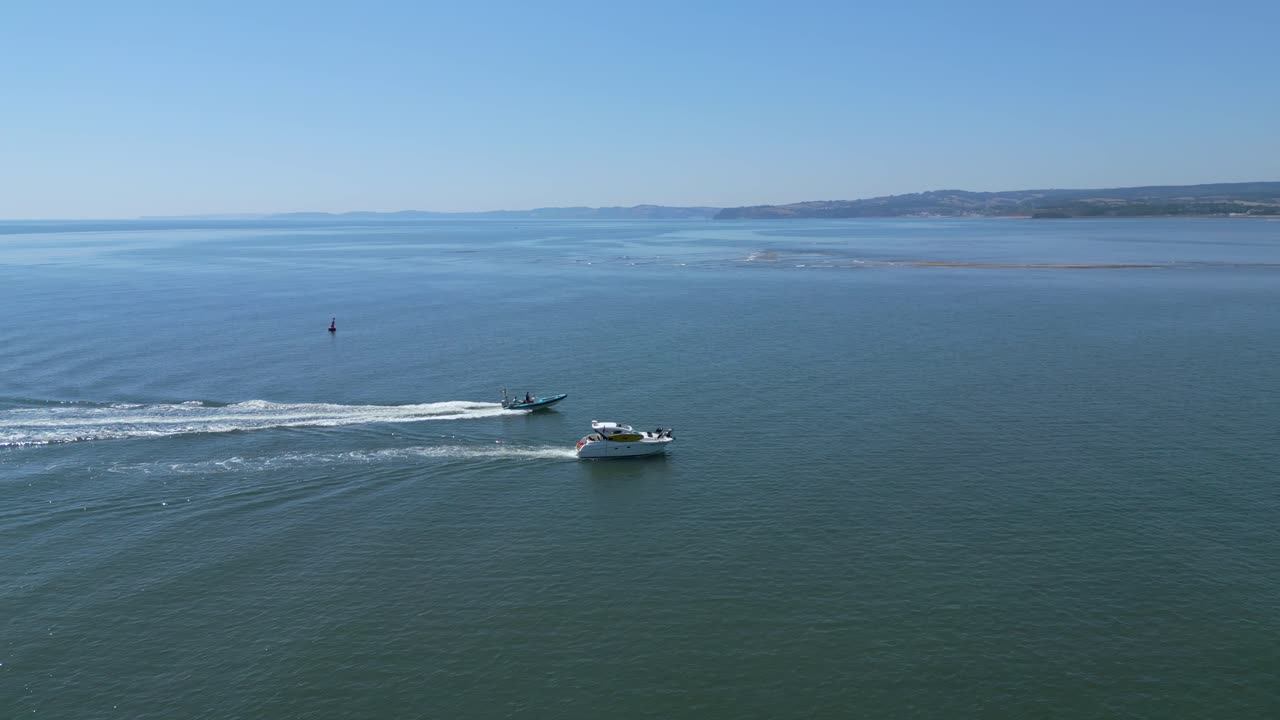 una lancha rápida pasa un pequeño yate en la playa de exmouth en devon con torbay en el fondo