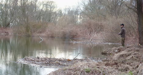 Man-Fishing-At-Lakeshore-In-Forest-9