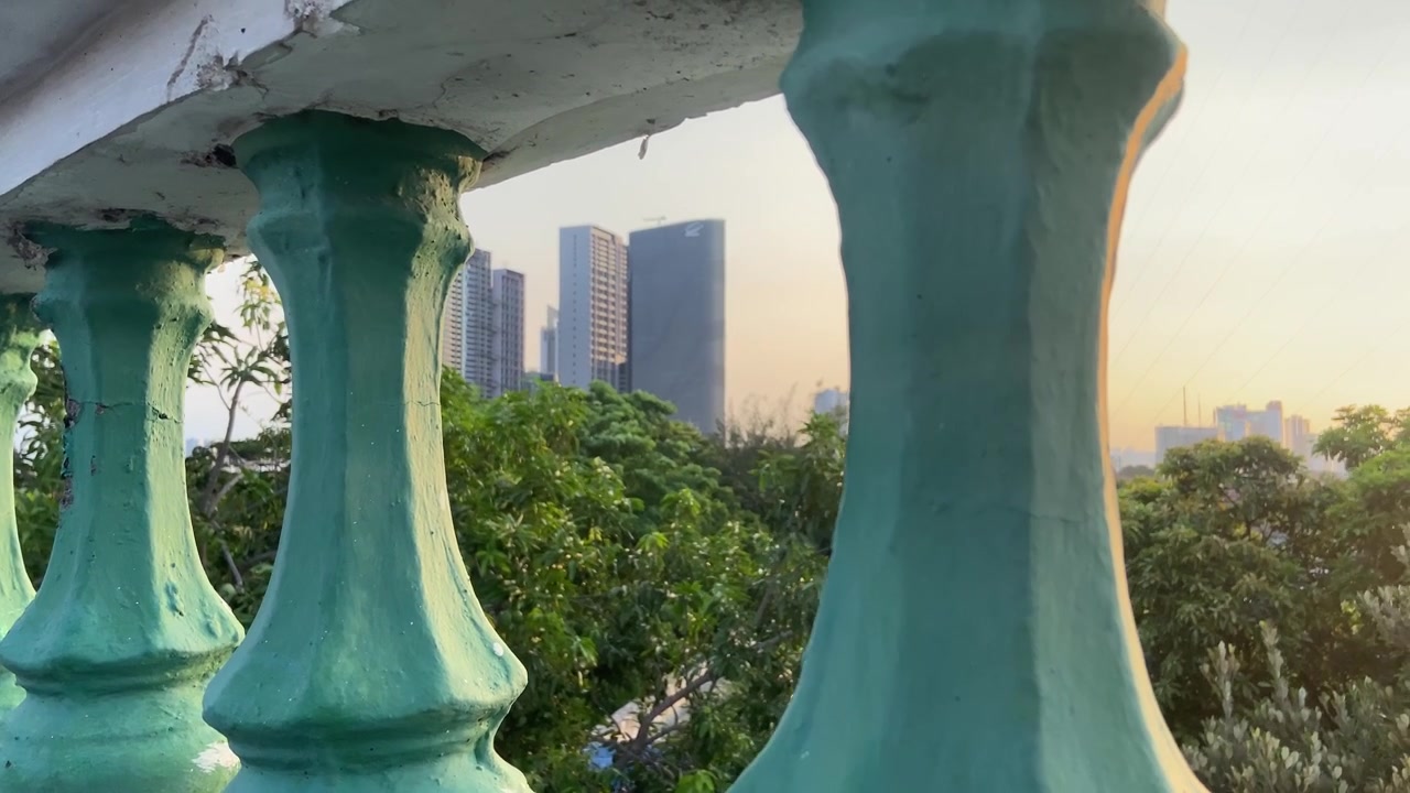 Vista Panorámica de la Ciudad con Edificios Modernos y Árboles Verdes a Través de una Balaustrada