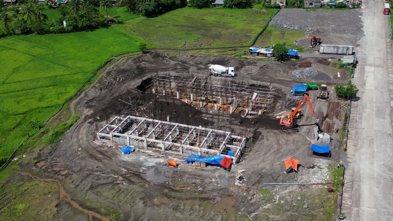 Angled drone orbit zoom in to construction zone exposed metal beams and machinery in Malilipot, Albay with clear views of project layout
