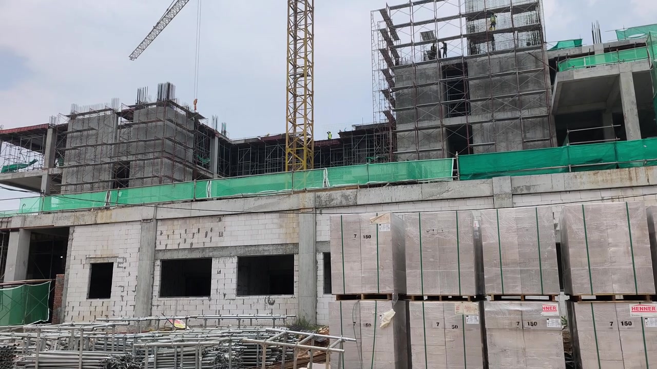 Construcción activa de un edificio de gran altura en curso. Se aplican estrictas medidas de seguridad en el lugar. Los materiales pesados están organizados de forma ordenada para un flujo de trabajo eficiente.