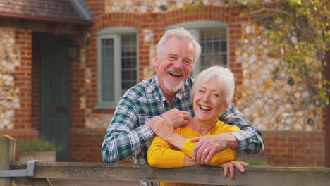 retrato de una feliz pareja de ancianos jubilados afuera de casa apoyados en la puerta