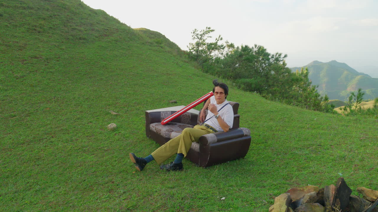 high angle view of young asiatic artist looking for an inspiration sitting in mountains valley green grass couch