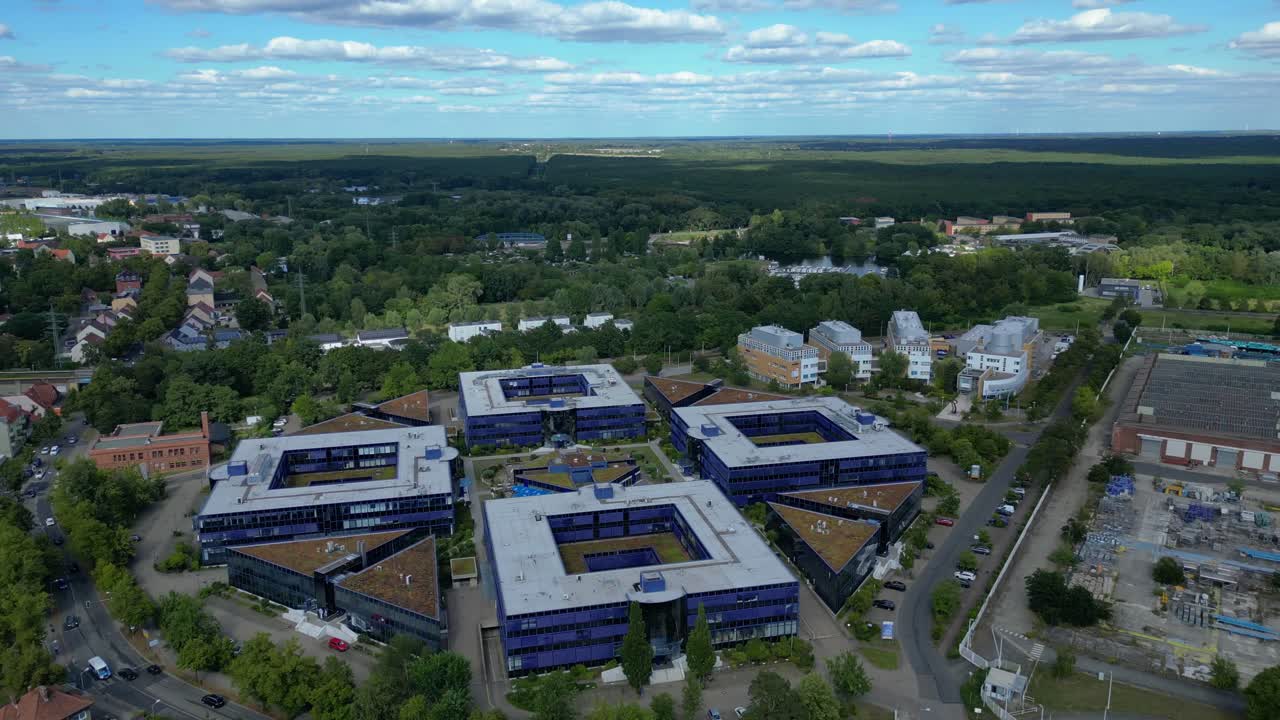 Hennigsdorf, Germany, showcasing residential areas, railway infrastructure and commercial buildings. Majestic aerial view flight wide orbit overview drone