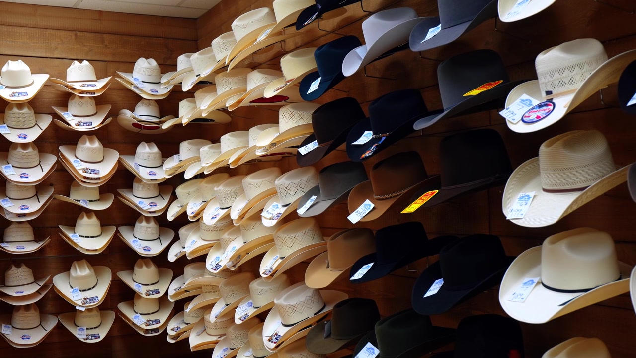 Parete di cappelli da cowboy bianchi e neri in un negozio al dettaglio western. Prospettiva diagonale di più file montate su pannelli di legno con etichette di prezzo