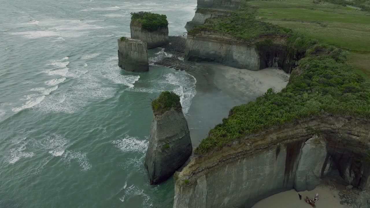 vista aérea sobre el paisaje costero de los acantilados de omau en el cabo de viento con olas ondulantes en la costa oeste de la isla sur, nueva zelanda aotearoa