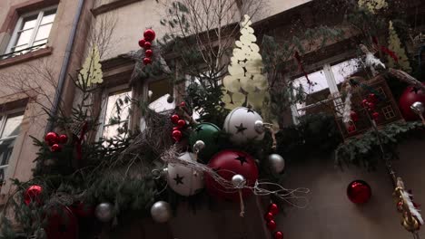 Christmas-bells-and-tree-and-tinsel-as-decoration-on-a-storefront-on-the-european-streets-of-Strasbourg,-France-at-a-Festive-Christmas-market-in-Europe