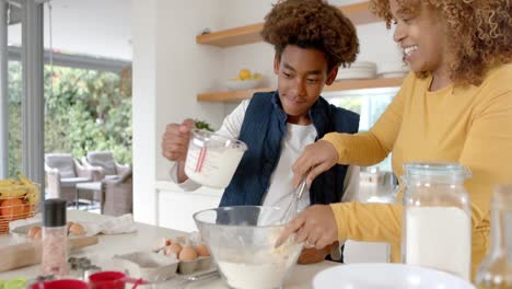 madre y hijo afroamericanos felices horneando en la cocina, cámara lenta