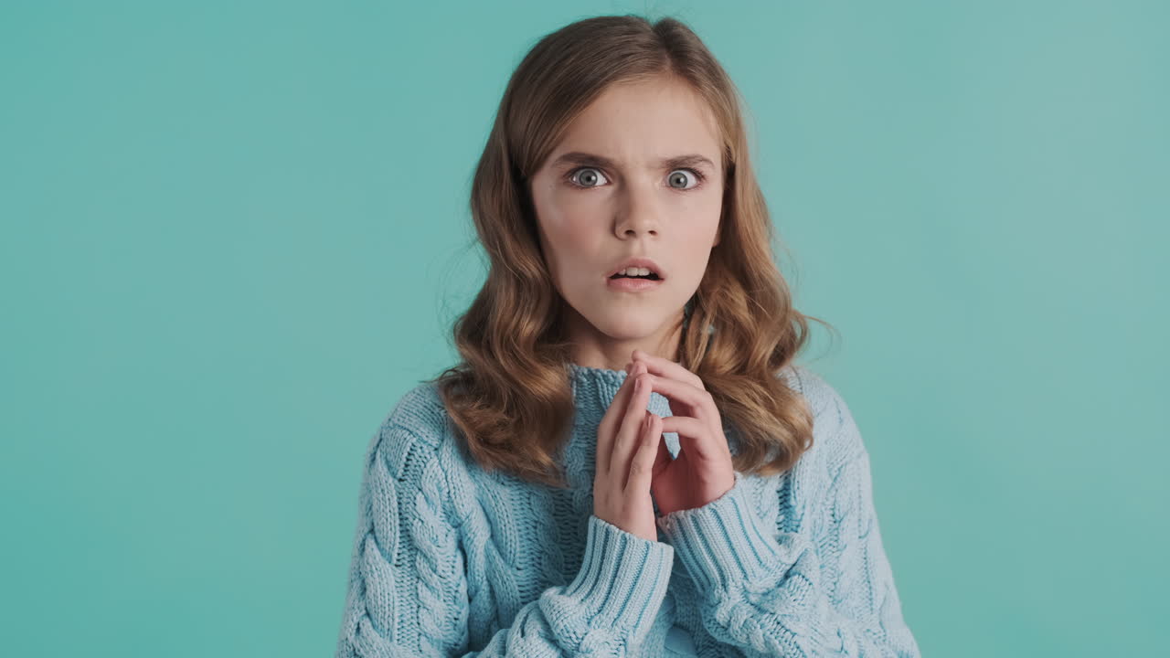 겁에 질린 십대 백인 소녀가 카메라 앞에서 눈을 감고 있습니다.