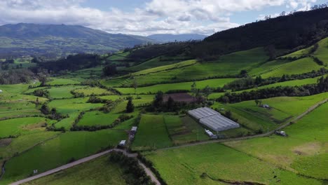 aerial drone flyover pull above green farms on foothills of the pasochoa volcano, puichig, showing the machachi valley, canton mejia, pichincha province, ecuador