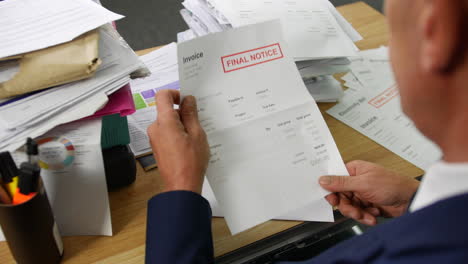 a man opening a stack of bills and letters with overdue notice for an invoice