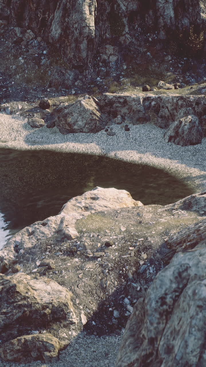 Costa rocciosa con acqua calma e spiaggia sabbiosa durante il giorno