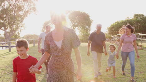 multi-generation family walking in countryside against flaring sun