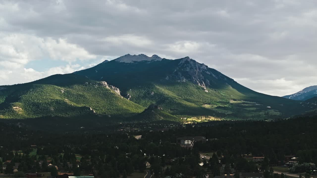 drone pan a la izquierda con vista al pico de la montaña rocosa con nieve en la parte superior, estes park colorado