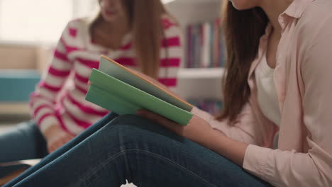 mujer lee un libro sentada en el piso de primer plano. el lector da la vuelta a las páginas aprendiendo el tema con su amiga en la biblioteca. estudiante universitario con el libro de texto en el interior