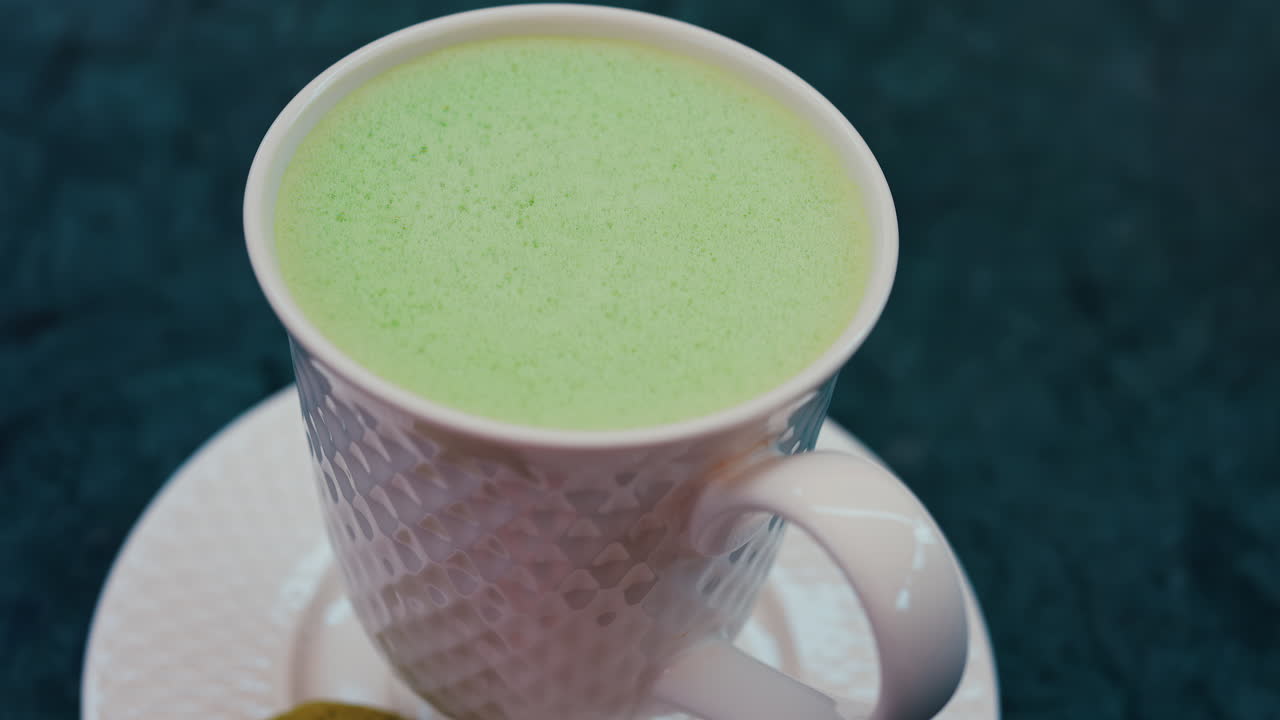 Close up of a smooth matcha latte with vibrant green foam in a white cup