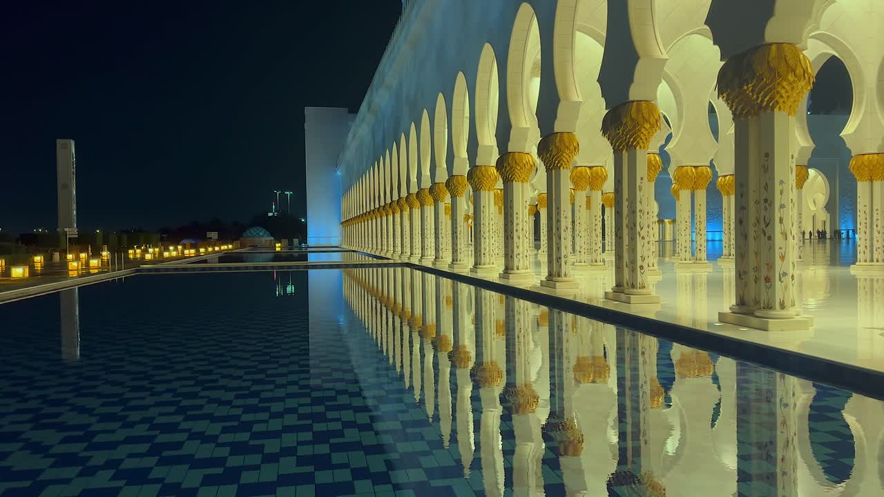 Lights of Grand Mosque portico reflect in shallow pool outside, Dubai