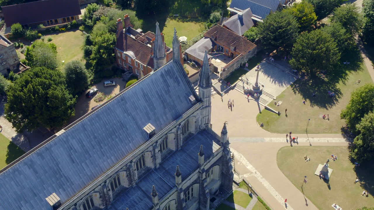 bajando el drone disparado sobre la catedral de winchester y los terrenos, capturado durante el verano en hampshire, reino unido
