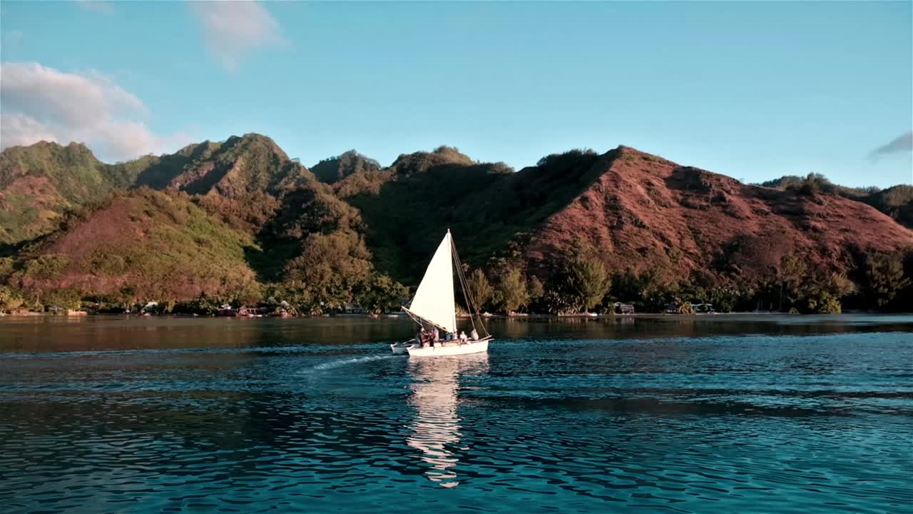 pequeño catamarán de vela navegando cerca de la isla de moorea en el pacífico sur